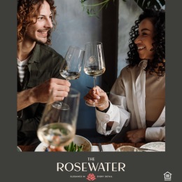 Cheers to securing a lifestyle upgrade when you find your fit at The Rosewater. Start your new chapter on our website. a man and a woman hold wine glasses and smile at each other